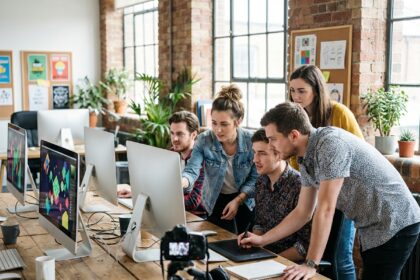 Groupe de professionnels créatifs autour d'écrans dans un studio moderne